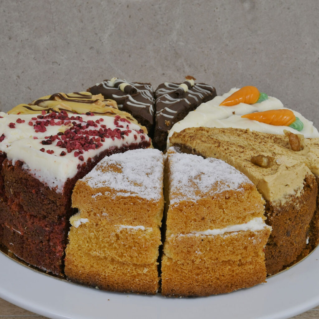 A 12 piece cake of 6 different flavors on a white plate with a grey background.